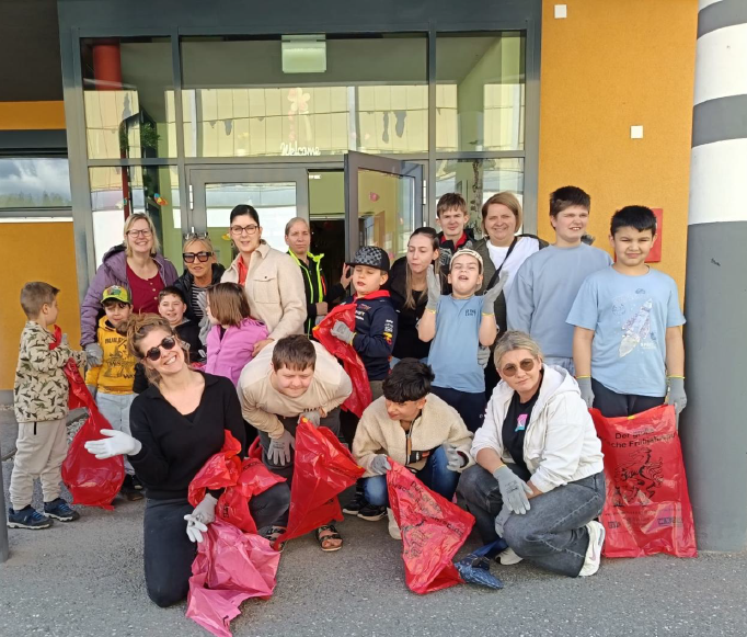 Sieben Lehrerinnen und zwölf Schüler die Spaß haben und Müllsäcke in den Händen halten